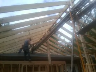 Rafters going up over a new addition with a worker on the wall in New London